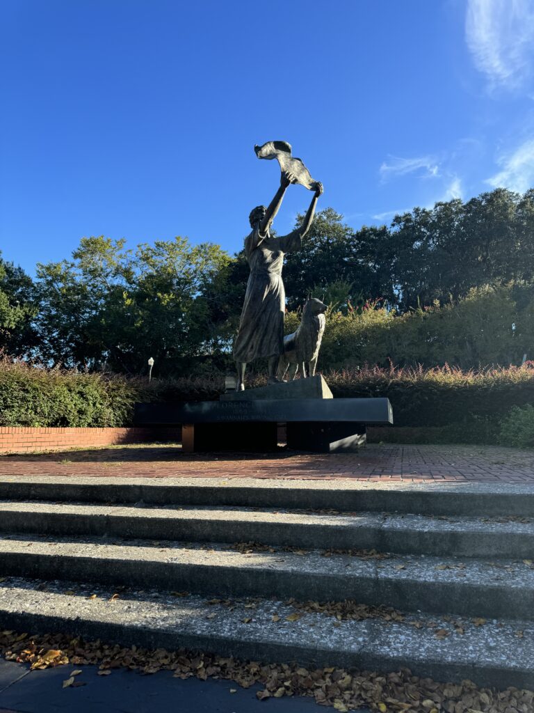 Statue of a woman waving a white sheet with her dog.