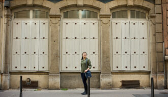 woman standing in front of 3 symmetrical windows in lyon, france