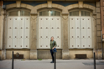 woman standing in front of 3 symmetrical windows in lyon, france