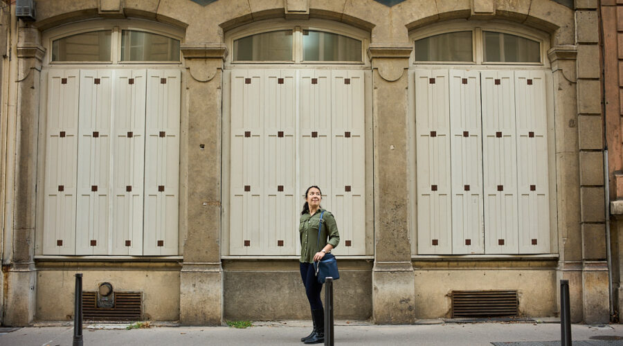 woman standing in front of 3 symmetrical windows in lyon, france