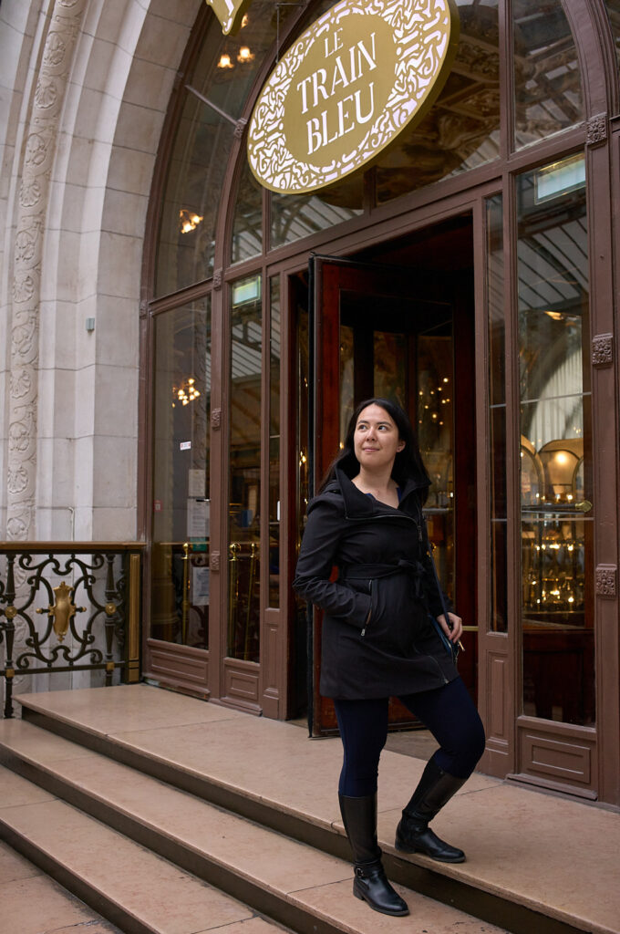 woman standing in front of a restaurant inside the paris train station.