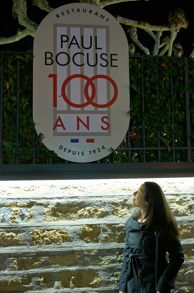 woman looking up at the paul bocuse sign lyon france