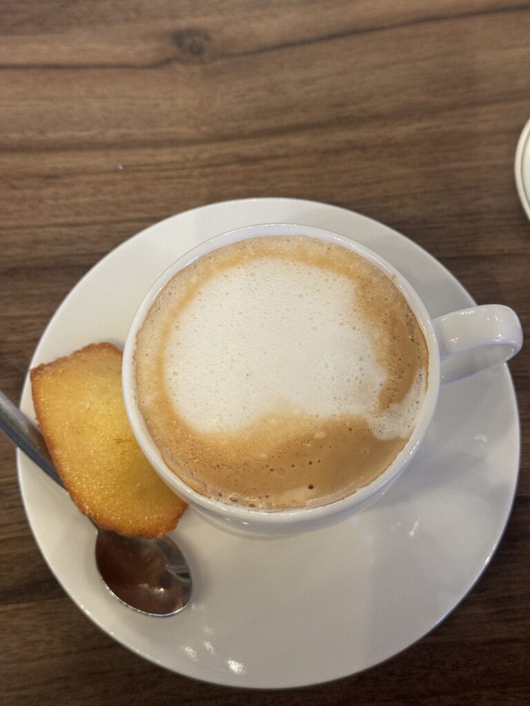 cup of coffee on a saucer with a piece of madelaine 