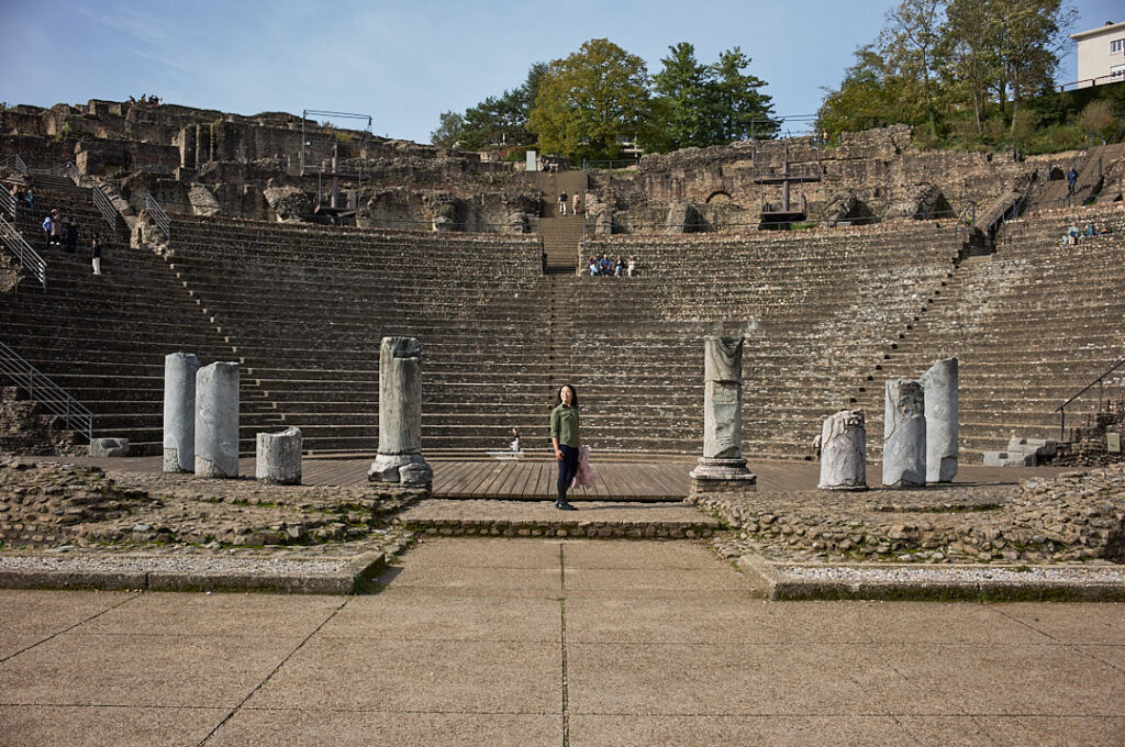 Woman standing in front of a roman amphitheatre in Lyon, France.